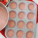Filling cupcake liners with strawberry cupcake batter before baking