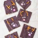 Reindeer crack toffee pieces topped with chocolate, pretzels, and candy eyes on natural parchment paper