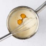 Add the eggs to the mixture one at a time and whisk until mixed together for the cinnamon roll bunny dough