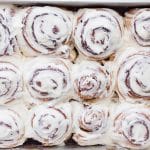 Cream cheese frosting spread over warm cinnamon rolls