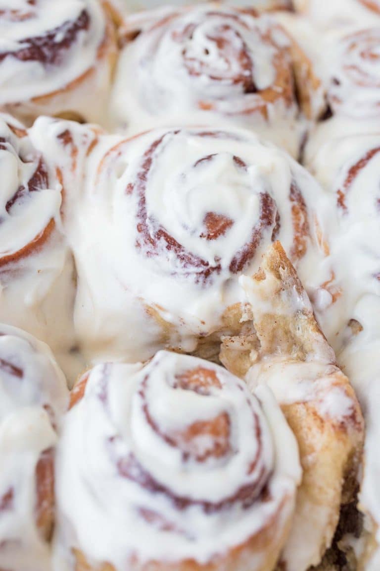 tangzhong cinnamon rolls in pan with Cream cheese frosting spread over warm cinnamon rolls