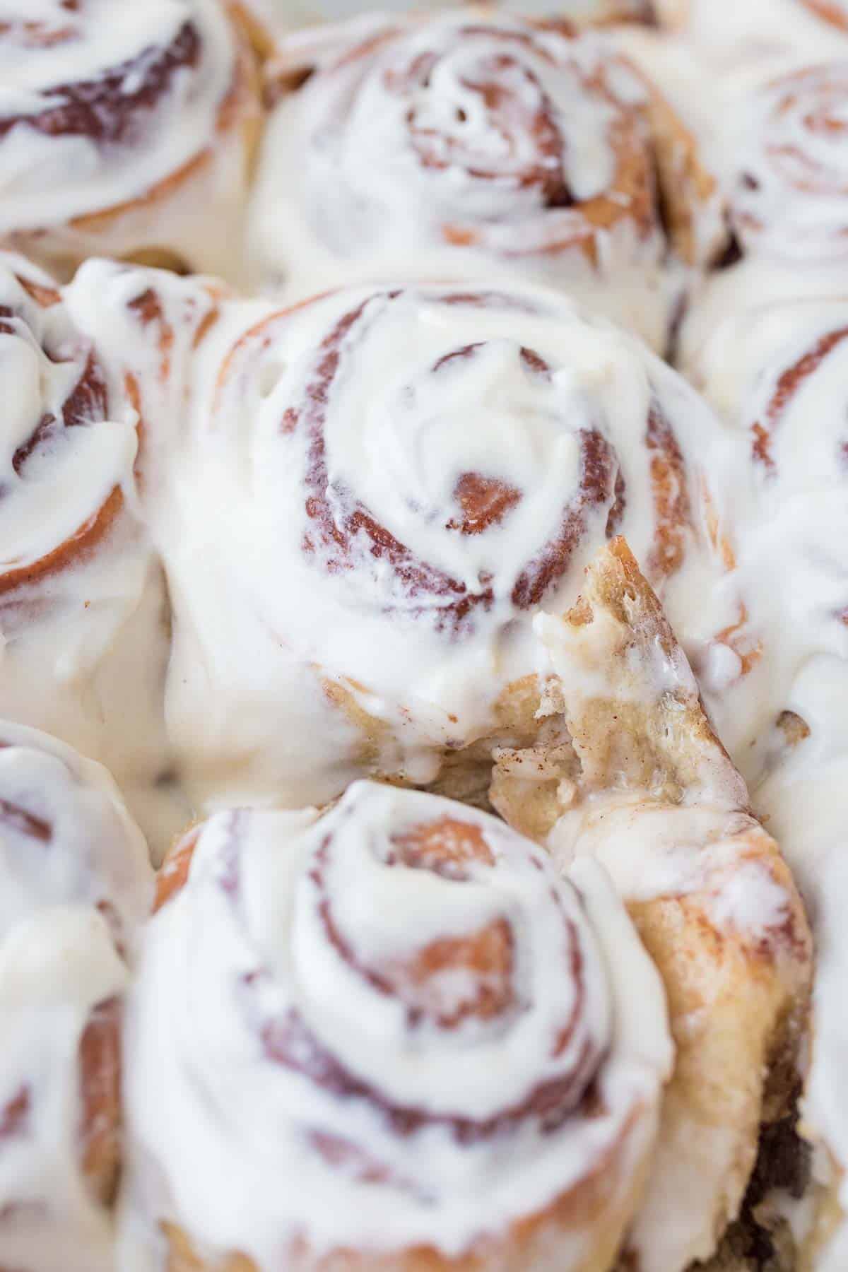 tangzhong cinnamon rolls in pan with Cream cheese frosting spread over warm cinnamon rolls