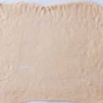 Dough rolled into a large rectangle on a floured surface for tangzhong cinnamon rolls