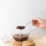 cashew butter reese egg being raised out of the dipped chocolate and letting the extra chocolate run off