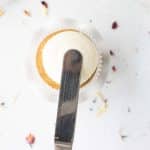 spatula making dent in icing to add honey for lemon honey cupcakes with cream cheese frosting