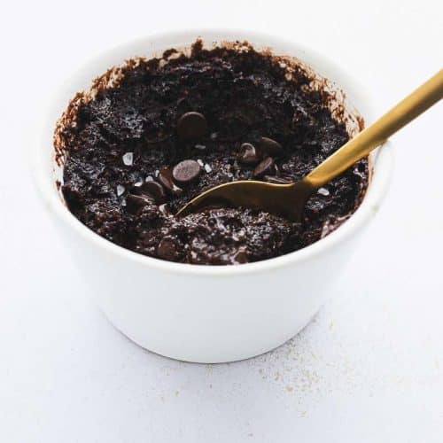 protein mug brownie cake in white ramekin with gold spoon taking a scoop