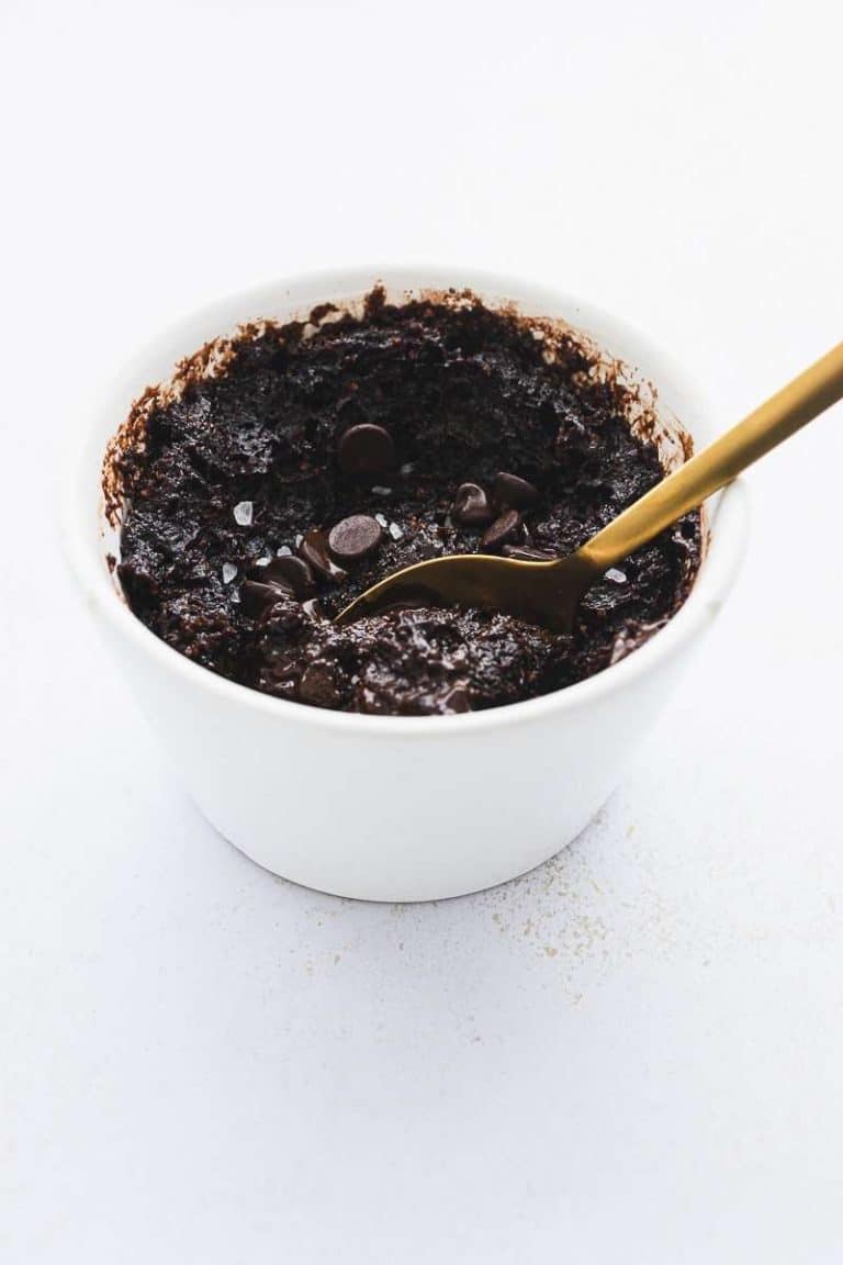 protein mug brownie cake in white ramekin with gold spoon taking a scoop