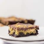 dubai chocolate avocado brownie slice on a white plate brownies in background