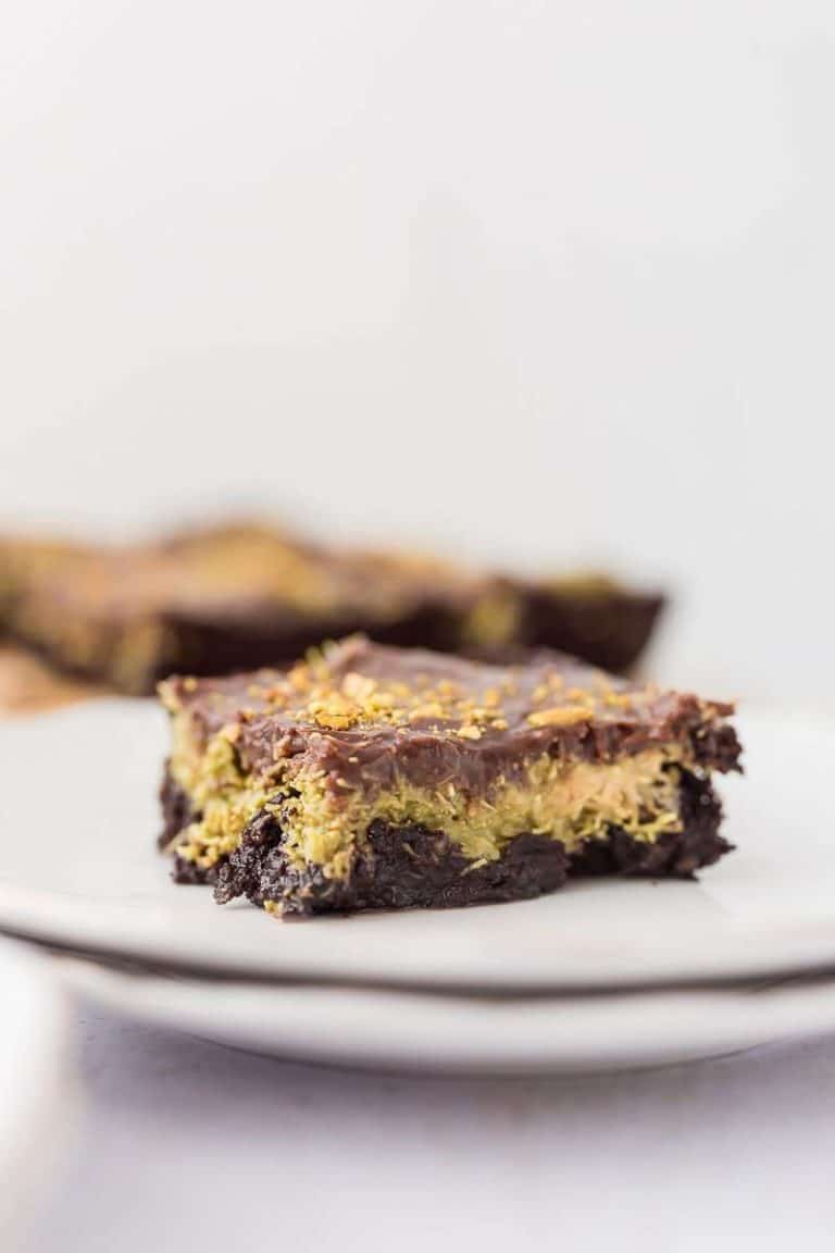 dubai chocolate avocado brownie slice on a white plate brownies in background