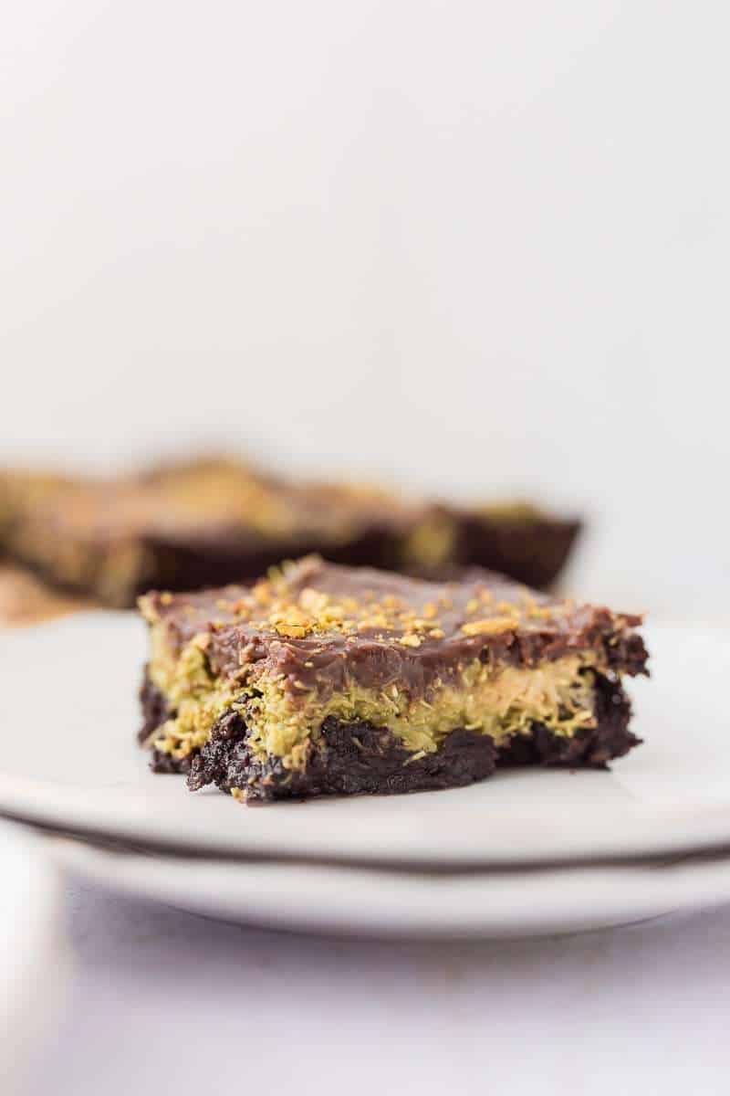 dubai chocolate avocado brownie slice on a white plate brownies in background