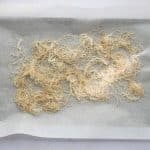 kataifi pastry mixed with coconut oil and cinnamon on a parchment lined baking sheet