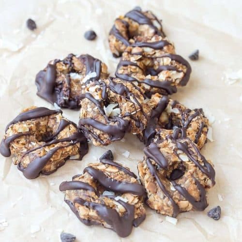 samoa cookies scattered on natural parchment paper with chocolate chips around
