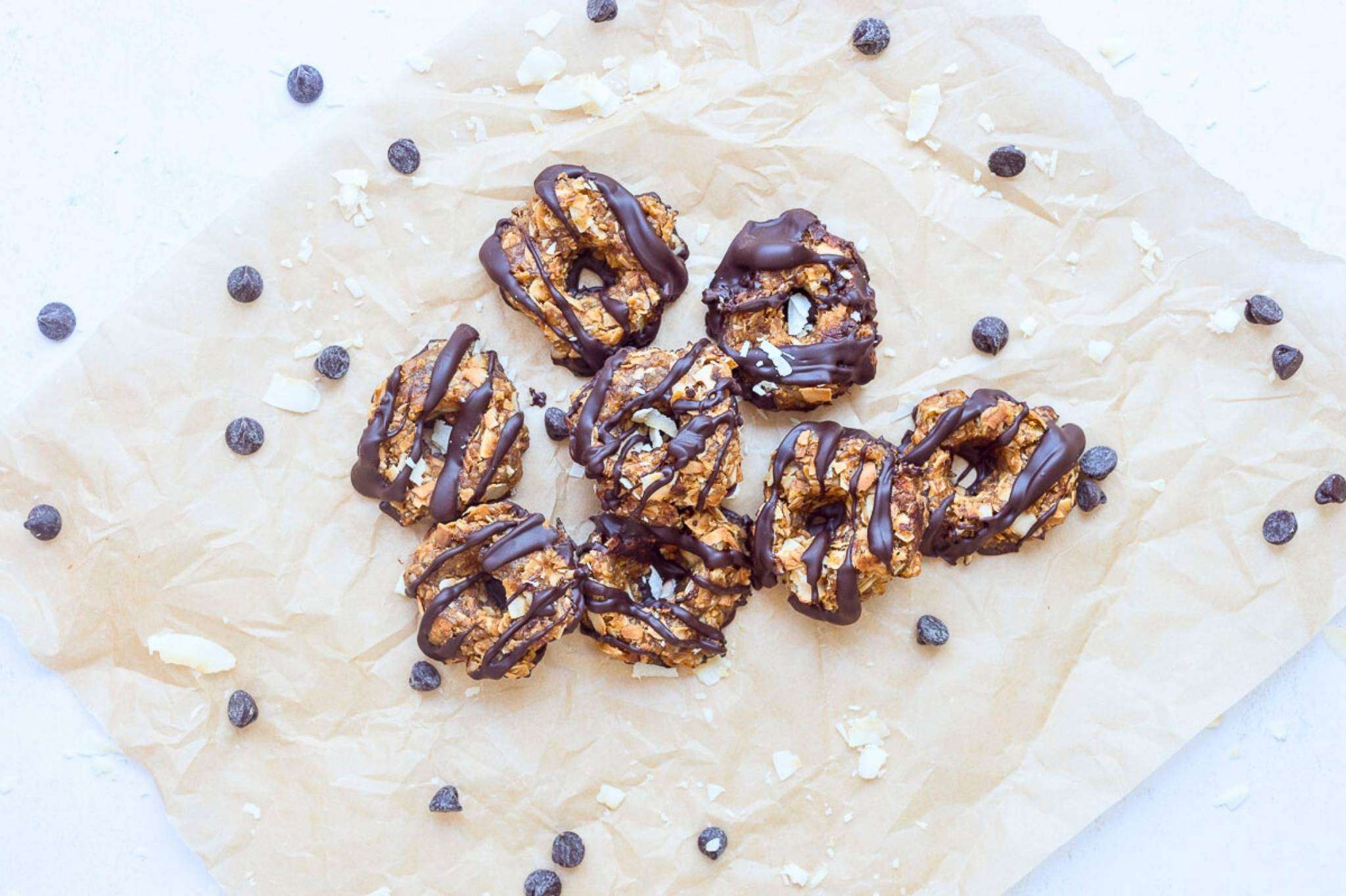 healthy samoa cookies on a natural parchment paper with chocolate chips scattered around.