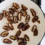 Pitted Medjool dates in a large ceramic cast iron saucepan with water on a stovetop