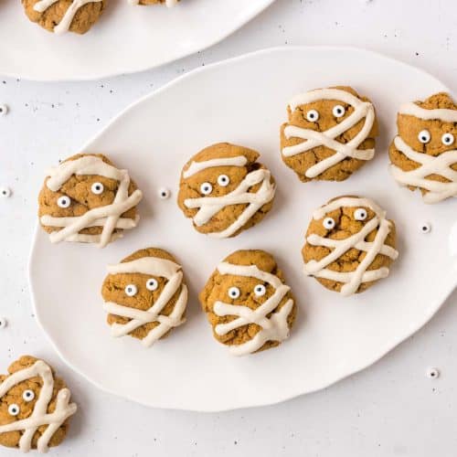 vegan pumpkin spice mummy cookies on a white scalloped plate