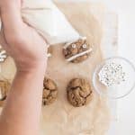 hand holding piping bag, piping mummy lines on vegan pumpkin spice cookie