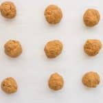 vegan pumpkin spice cookie dough rolled into balls on parchment lined baking pan