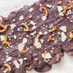 melted chocolate poured over the date layer, topped with pretzels and almond flour crackers for making christmas crack date bark.