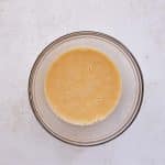 Whisking eggs, melted coconut oil, and vanilla extract in a bowl for protein bar dough.