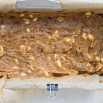 Spreading peanut-date caramel over chilled nougat layer to assemble high-protein Snickers bars.