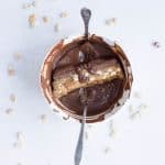 Dipping each homemade Snickers protein bar into melted chocolate for a candy-bar style finish