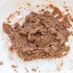 Mixing almond flour, Snickers protein powder, maple syrup, almond milk, and coconut oil to make the nougat layer for homemade high-protein Snickers protein bars.