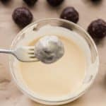 Dipping chocolate peppermint protein balls into melted white chocolate coating.