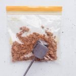 Biscoff cookie pieces in zip top bag being crushed with mallett