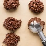 Biscoff chocolate quinoa mixture being scooped onto a baking sheet with a cookie scoop.