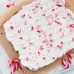 Peppermint sugar cookie bars iced before being cut on piece of natural parchment paper