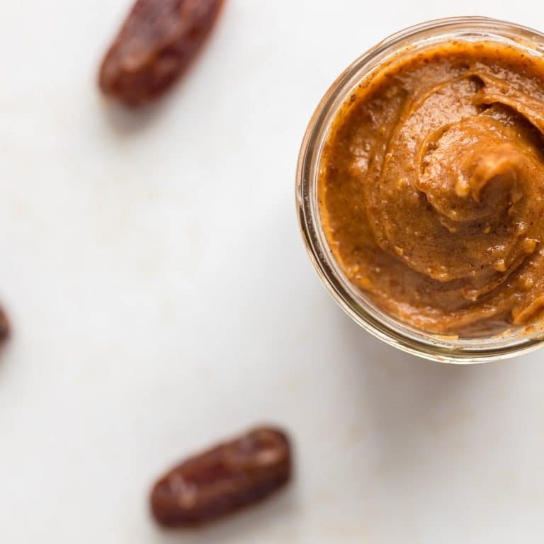 overhead shot of date caramel sauce in jar in top right corner with dates around