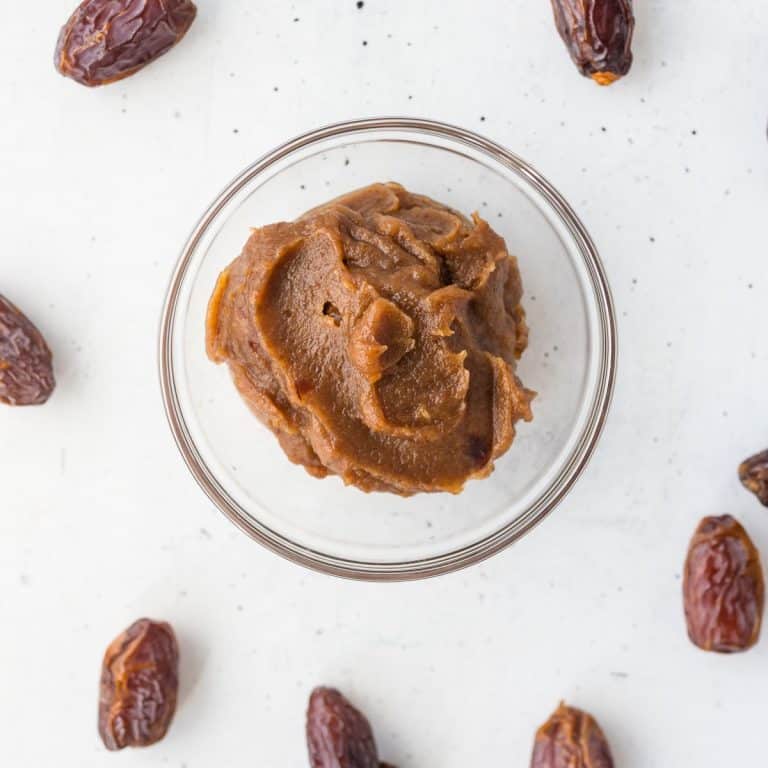 date paste in clear glass bowl with dates around on white surface