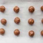 Chilled gingerbread energy bites on a parchment lined tray before dipping
