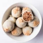 Healthy gingerbread energy bites coated in white chocolate in a white bowl on a white surface