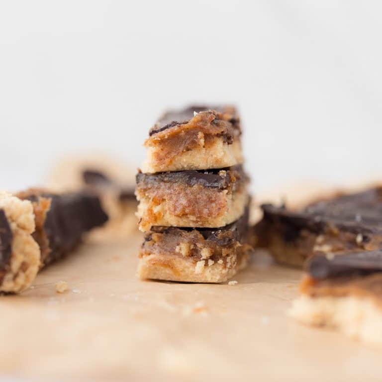 Stack of three healthy Twix bars on parchment paper with extra bars surrounding