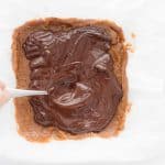 Smoothing the chocolate layer evenly across the Twix bars