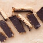 Healthy homemade Twix bars scattered on natural parchment paper with chocolate coating and date caramel layers