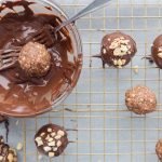 Snickers protein balls being dipped in melted dark chocolate