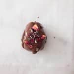 Strawberry cheesecake stuffed date sprinkled with freeze-dried strawberry crumbs, cacao nibs and rose petals.