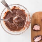 Using a fork or spoon, dip each stuffed date into the melted chocolate, coating it fully.