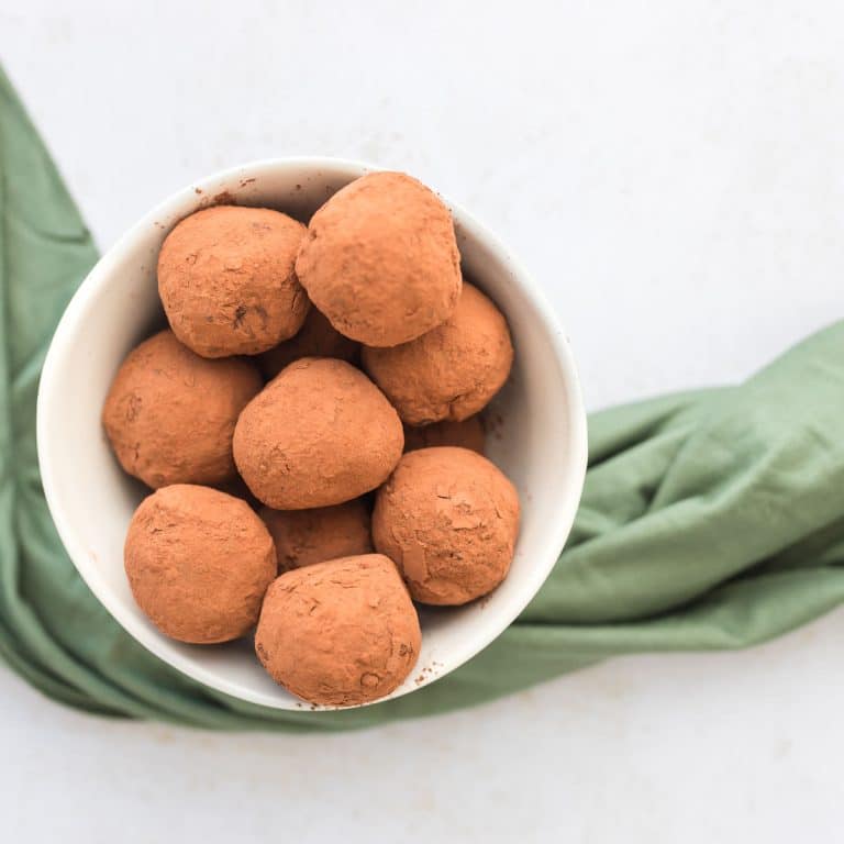overhead image of Baileys chocolate protein truffles in a white ceramic bowl with green napkin