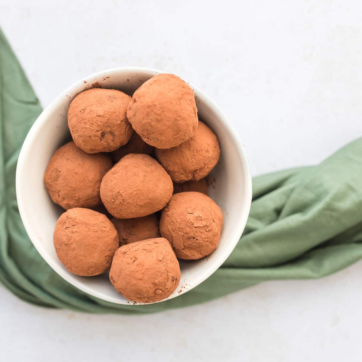 overhead image of Baileys chocolate protein truffles in a white ceramic bowl with green napkin