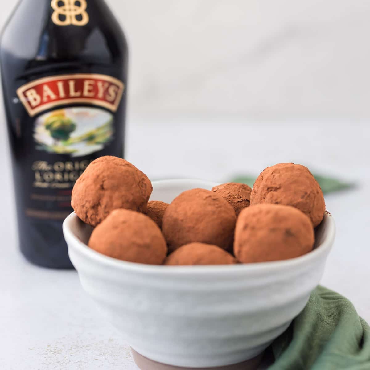 baileys chocolate protein truffles in white bowl with baileys in background