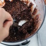 scooping chocolate protein truffle mixture with cookie scoop