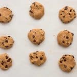 Scooping chocolate chip protein cookie dough onto lined baking sheet and flattening
