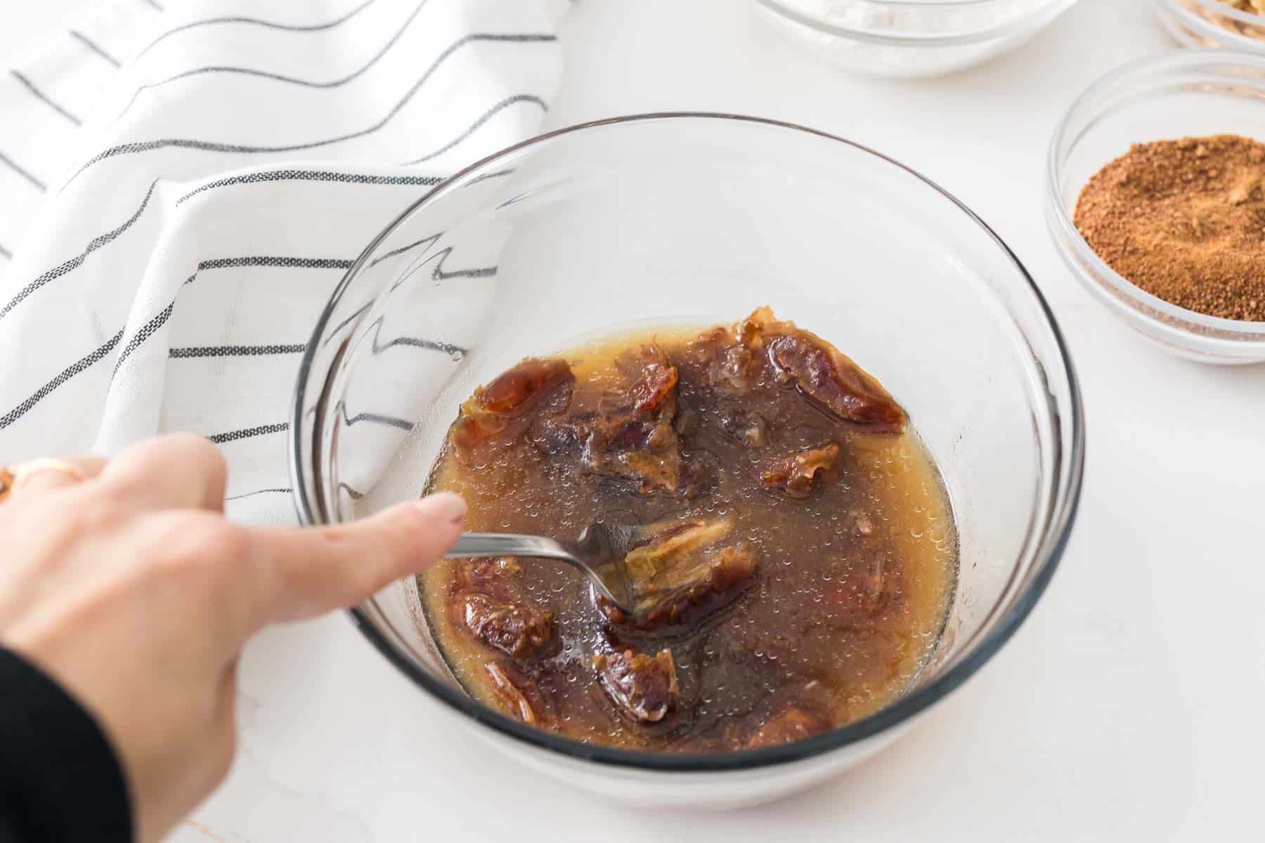 Mashing the dates directly in the bowl using a fork until thick and caramel-like for the date cake