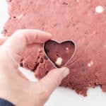 Use a 1” heart-shaped cookie cutter to cut out hearts from the edible red velvet cookie dough