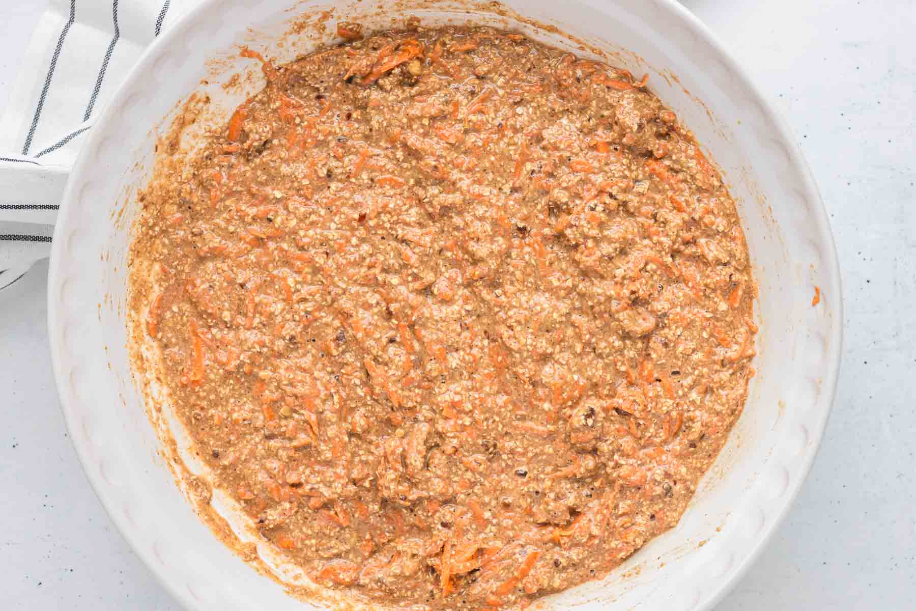 Fold in the shredded carrots and chopped walnuts for the mini carrot cakes