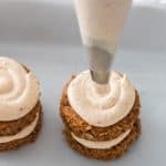 piping cream cheese frosting on top layer of mini carrot cake