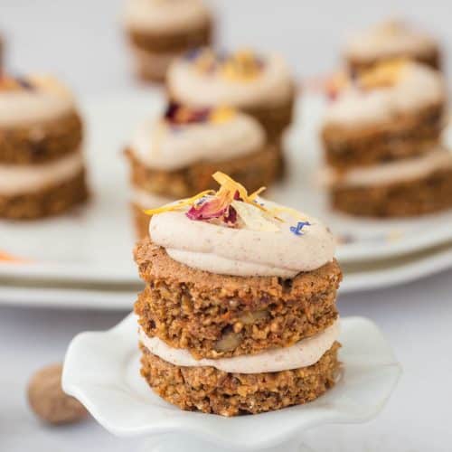 mini carrot cake on cupcake stand with others on decorative plate in background